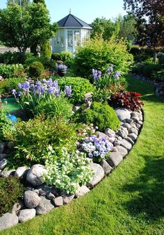 a garden filled with lots of different types of flowers and plants next to a house