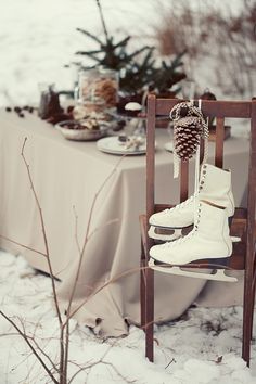 two pairs of ice skates are sitting on a chair in the snow near a table