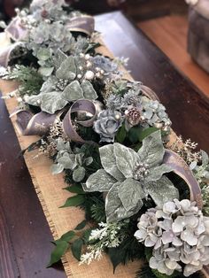 a wooden table topped with flowers and greenery