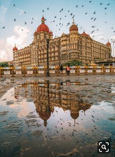 birds are flying in the sky over a large building