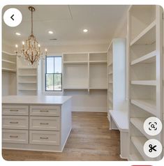 an empty room with white cabinets and chandelier