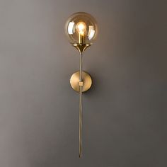 a wall mounted light on the side of a gray wall with a round glass shade