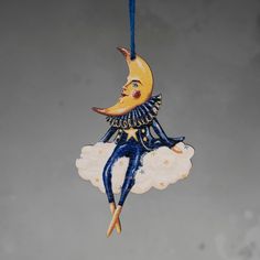 a ceramic ornament hanging from a string with a crescent moon and stars on it