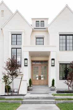 a large white house with two story windows and steps leading up to the front door