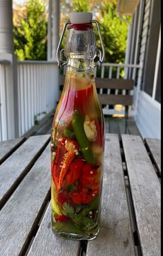 a glass bottle filled with liquid sitting on top of a wooden table next to a porch