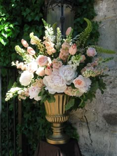 a gold vase filled with lots of pink and white flowers