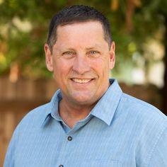 a man in a blue shirt smiling at the camera