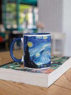 a coffee mug sitting on top of a book with the starry night painting on it