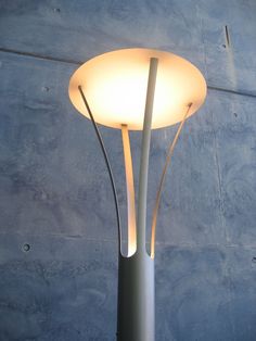 a lamp that is on top of a metal pole with a white light inside it