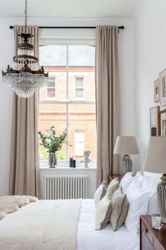 a bedroom with a chandelier hanging from the ceiling next to a large window