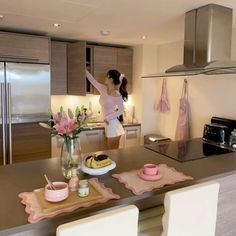 a woman standing in a kitchen next to a table with plates and cups on it