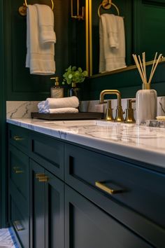 a bathroom with green walls and marble counter tops, gold faucets and brass fixtures