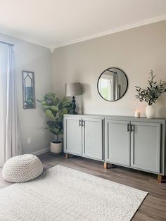 a living room with a rug, mirror and plant on the sideboard in front of it