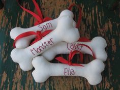 three bone ornaments with names on them are sitting on a table next to a red ribbon