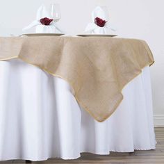 two white vases sitting on top of a table covered in a burlock