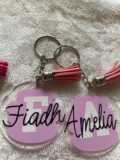 two personalized acrylic keychains with tassels attached to them