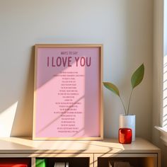 a pink poster with the words i love you on it next to a book shelf