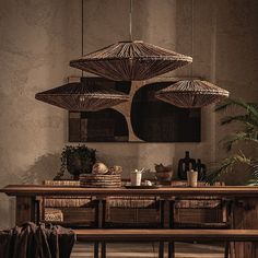 a wooden table topped with lots of wicker baskets under hanging umbrellas over it