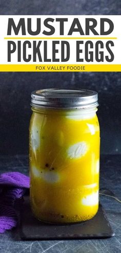 a mason jar filled with pickled eggs sitting on top of a table next to a purple towel