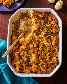 a casserole dish filled with stuffing and topped with a wooden spoon next to other dishes