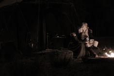 a woman sitting next to a fire in the dark