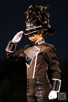 a woman in a uniform is holding her hand up to her face as she walks down the runway