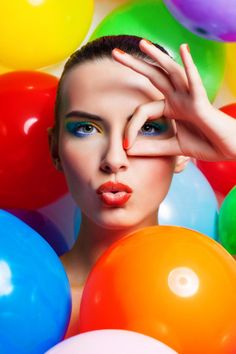 a woman surrounded by balloons with her hands on her face