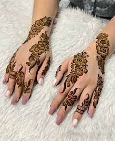 two hands with henna tattoos on them