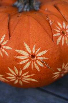 an orange pumpkin with white flowers painted on it