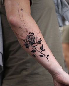 a person with a tattoo on their arm holding onto a flower and cross tattoos in the background