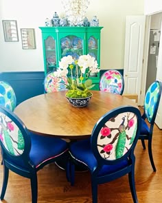 a dining room table with blue chairs and flowers in a vase on top of it