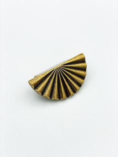 an antique brass fan shaped brooch on a white background