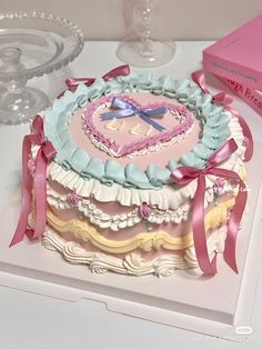 a heart shaped cake sitting on top of a table next to a pink box and wine glasses