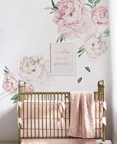 a baby's room with pink flowers on the wall and a gold crib