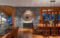 a living room filled with furniture and a stone face on the wall above a wooden dining table