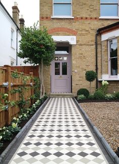 a black and white checkered floor in front of a brick building with a purple door