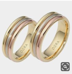 two gold and silver wedding rings with the word doxa engraved on each side,