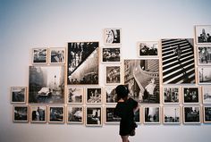 a person standing in front of a wall with many pictures hanging on it's sides