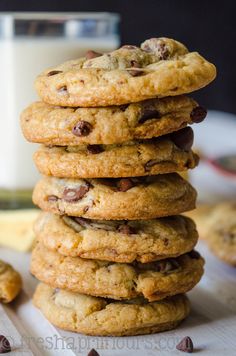 chocolate chip cookies stacked on top of each other with a glass of milk in the background