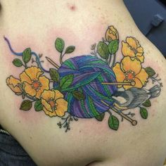 a woman with a tattoo on her back holding a ball of yarn and yellow flowers