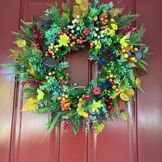 a wreath is hanging on the front door with autumn foliages and berries around it