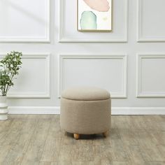 a small round ottoman sits in front of a white wall