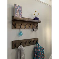 two wooden shelfs with hooks on them are hanging from the wall next to a coat rack