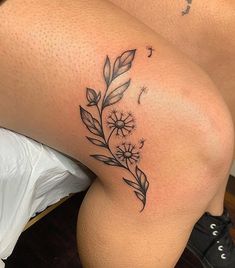 a woman's thigh with a flower tattoo on her left leg and an arrow in the middle