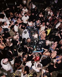 a large group of people standing around a dj's booth at a music festival