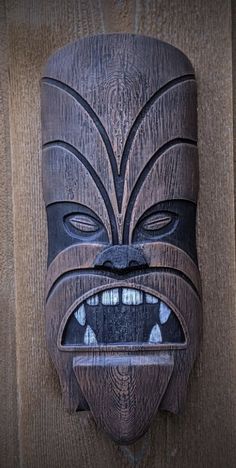 a wooden mask hanging on the side of a wall