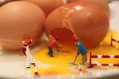 miniature people are playing with eggs on a plate