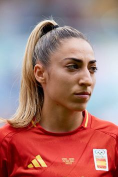 a female soccer player wearing a red shirt and ponytail with her hair in a pony tail