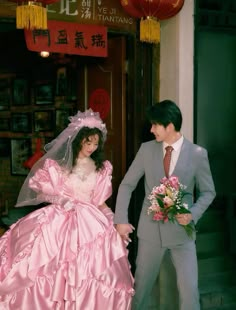 a man and woman dressed up in formal wear standing next to each other on the street