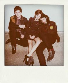 two young people sitting next to each other on the ground with their legs crossed and one person wearing high heeled shoes